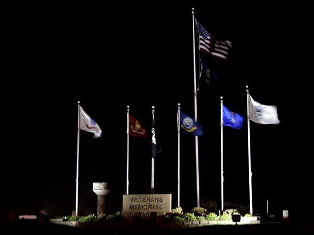Flags flutter at night in front of a illuminated monument